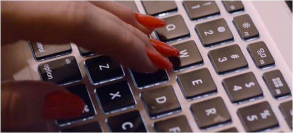 Mulher usando esmalte e digitando no computador