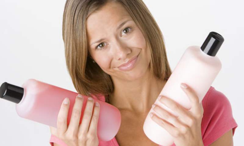 mulher segurando shampoo e condicionador nas mãos