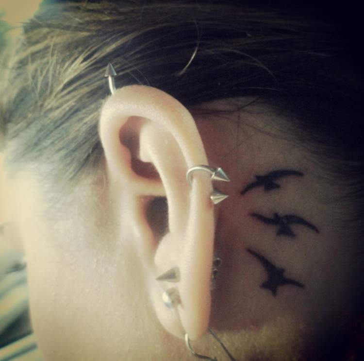 Tatuagem de pássaros voando atrás da orelha