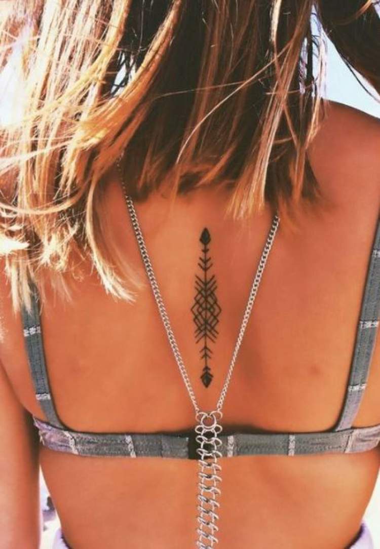 Tatuagem delicada nas costas com o desenho de uma flecha