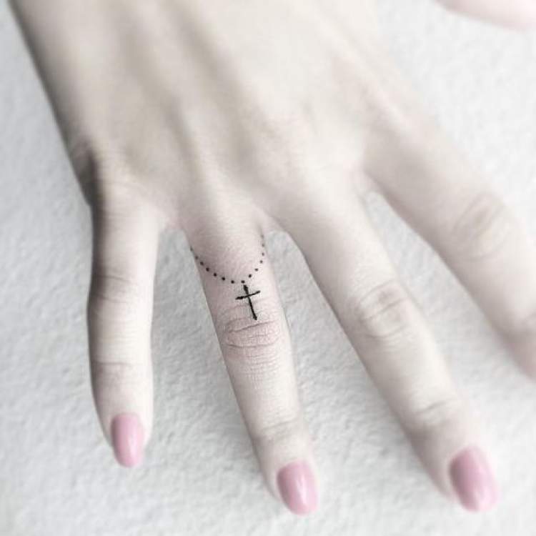 Tatuagem religiosa no dedo da mão