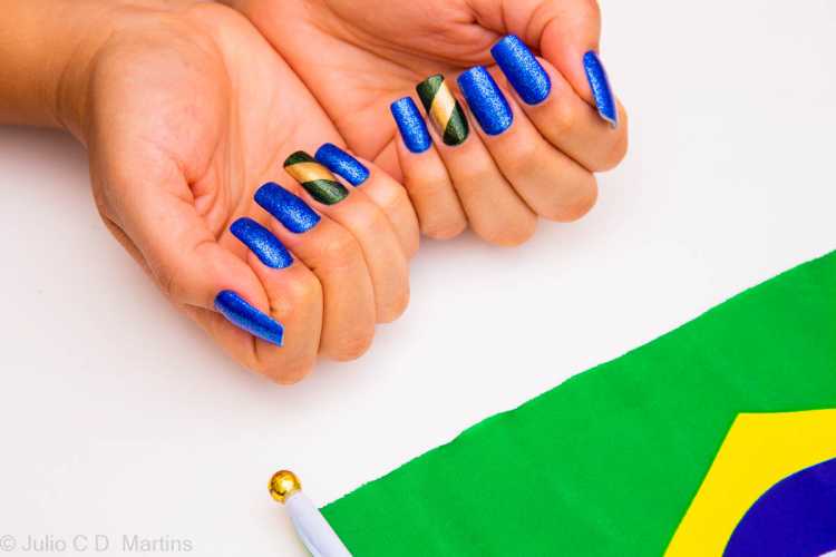 Bem clássicas, as unhas azuis ficam incríveis com uma filha única com as cores da bandeira brasileira em glitter.