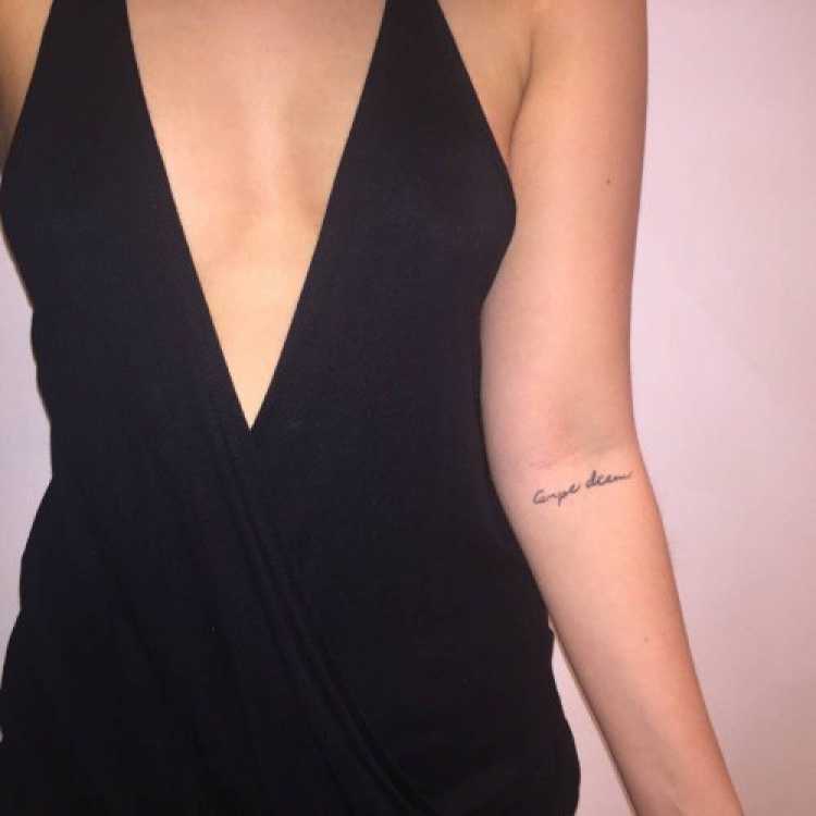 Mulher com dizeres tatuados no braço