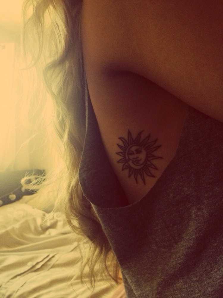 Mulher com o desenho do sol tatuado na costela embaixo do braço