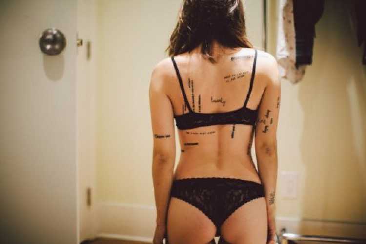 Mulher com várias palavras tatuadas no corpo