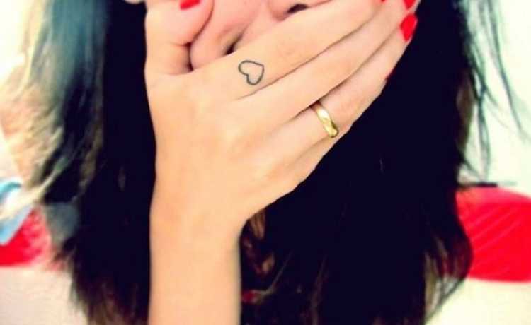 Tatuagem feminina no dedo da mão no formato de um coração