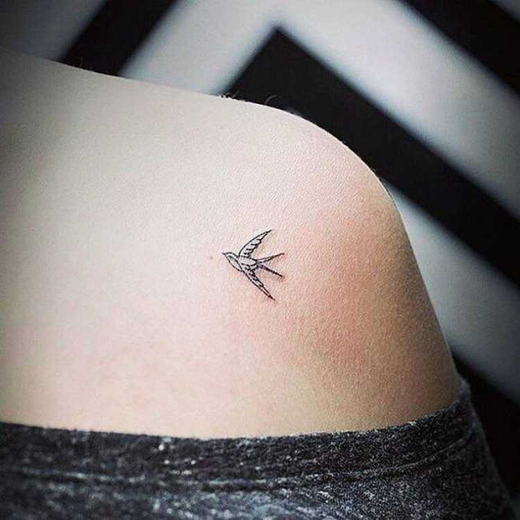 Tatuagem feminina delicada com um passarinho no ombro