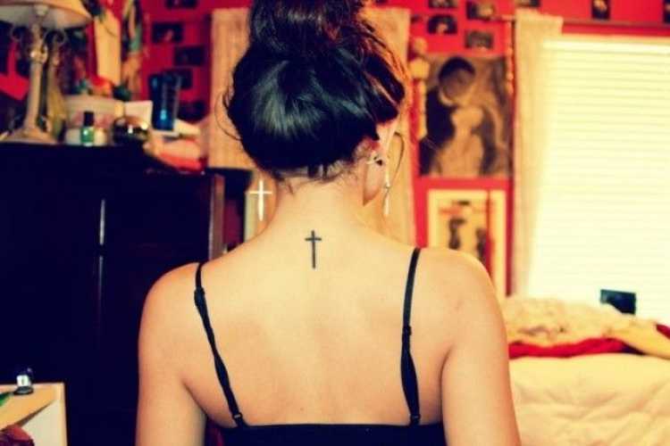 Tatuagem feminina no formato de um crucifixo na parte de trás do pescoço