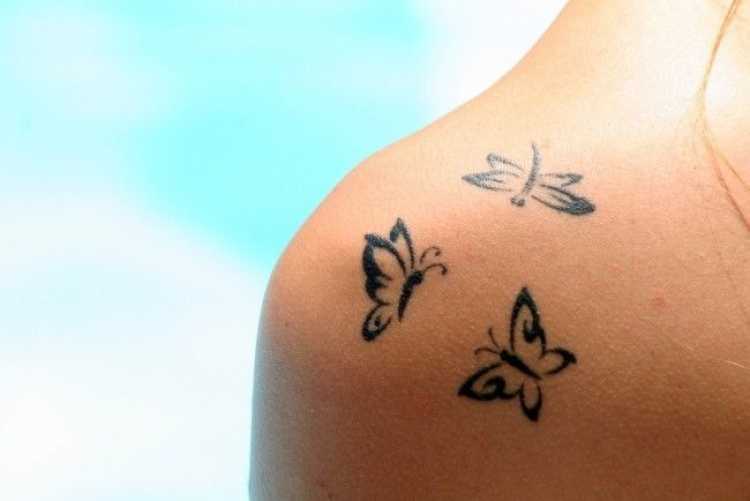 Tatuagem no ombro com o desenho de três borboletas