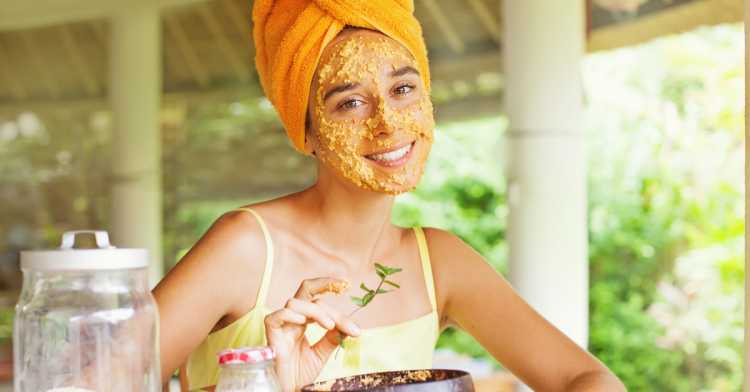 Mulher aplicando máscara caseira e natural de mel e mamão no rosto